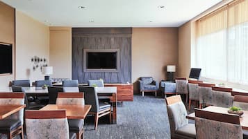 A conference room with a large TV, multiple tables and chairs, and a carpeted floor.