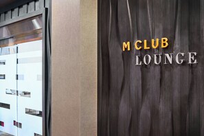 A wall with the text 'M CLUB LOUNGE' in bold letters.