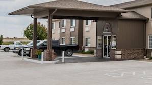 L’entrée d’un hôtel avec un espace de stationnement couvert, une façade en briques et un ciel dégagé.