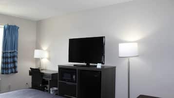 Habitació d'hotel amb llit, escriptori amb ordinador, televisió de pantalla plana, microones i làmpada.