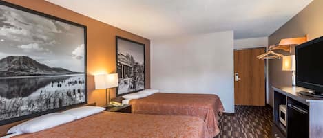 Habitació d'hotel amb dos llits, televisió, escriptori amb làmpada i obres d'art a les parets.