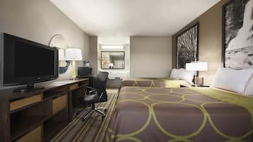A hotel room with a large bed, a desk with a TV, a chair, and a desk lamp.