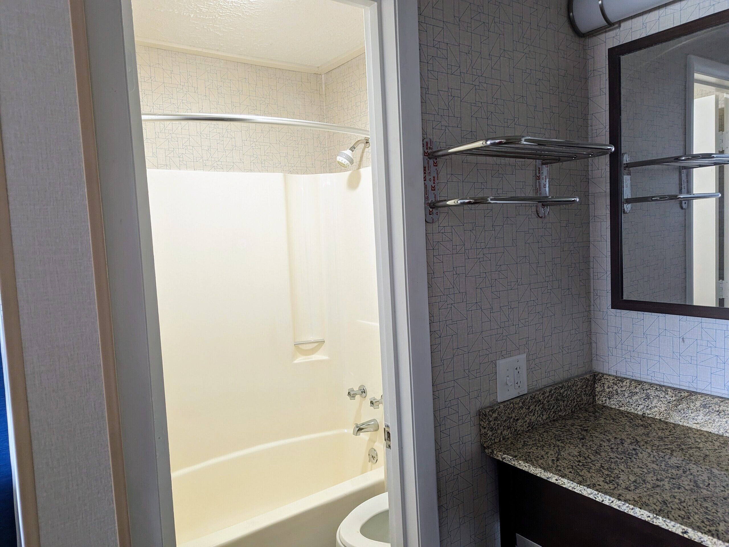Une salle de bain avec douche, toilettes et un comptoir en granit.