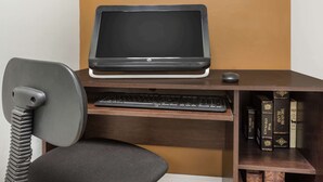 Ein Computertisch mit Bildschirm, Tastatur und Stuhl.