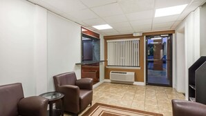 Ein Hotelzimmer mit Sitzecke, ausgestattet mit zwei braunen Ledersofas, einem Couchtisch mit Glasplatte und einem Teppich in Braun. Eine Glastür führt auf einen Balkon mit Blick ins Freie.