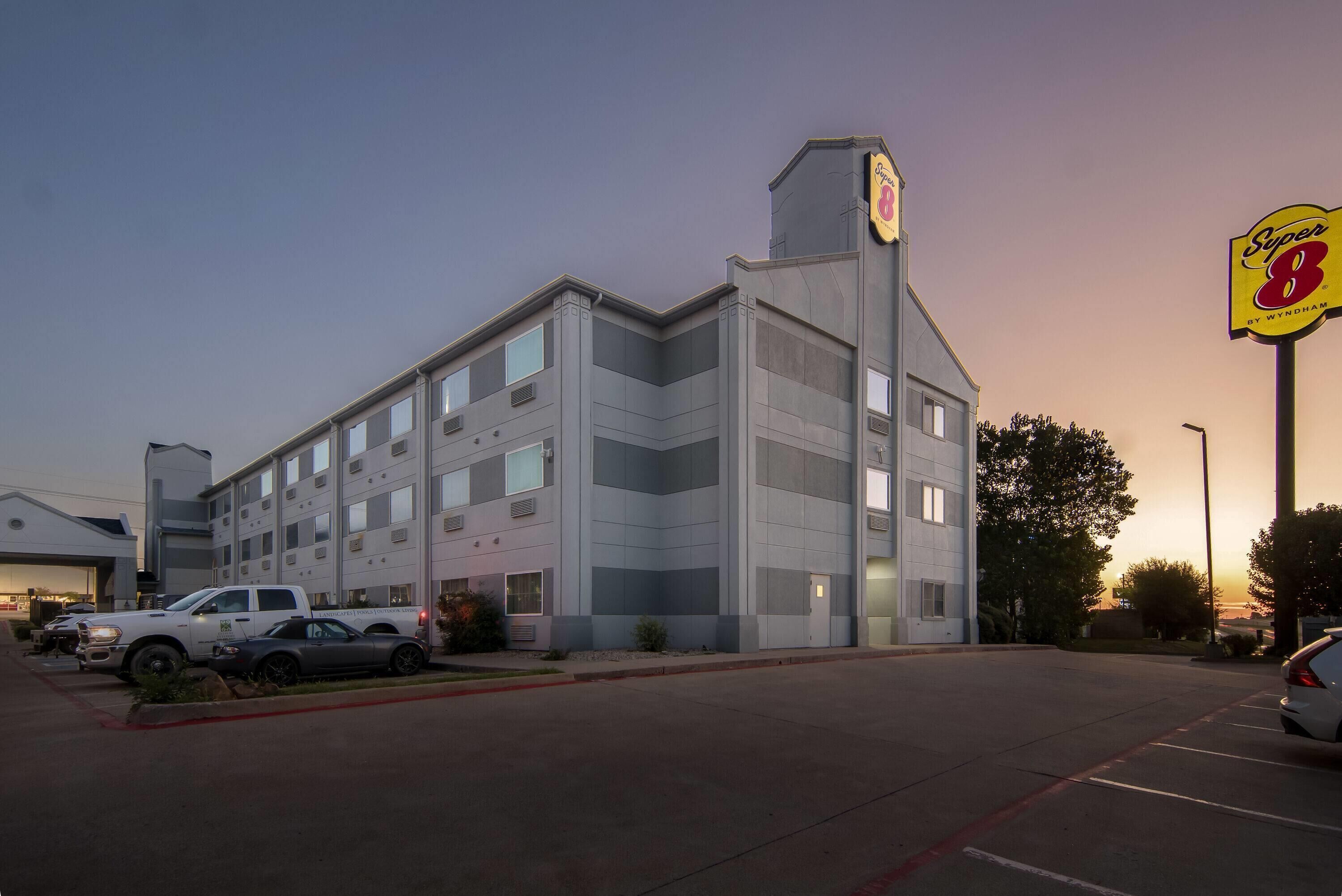 A multi-story hotel with a prominent 'Super 8' sign, parking lot, and adjacent buildings.