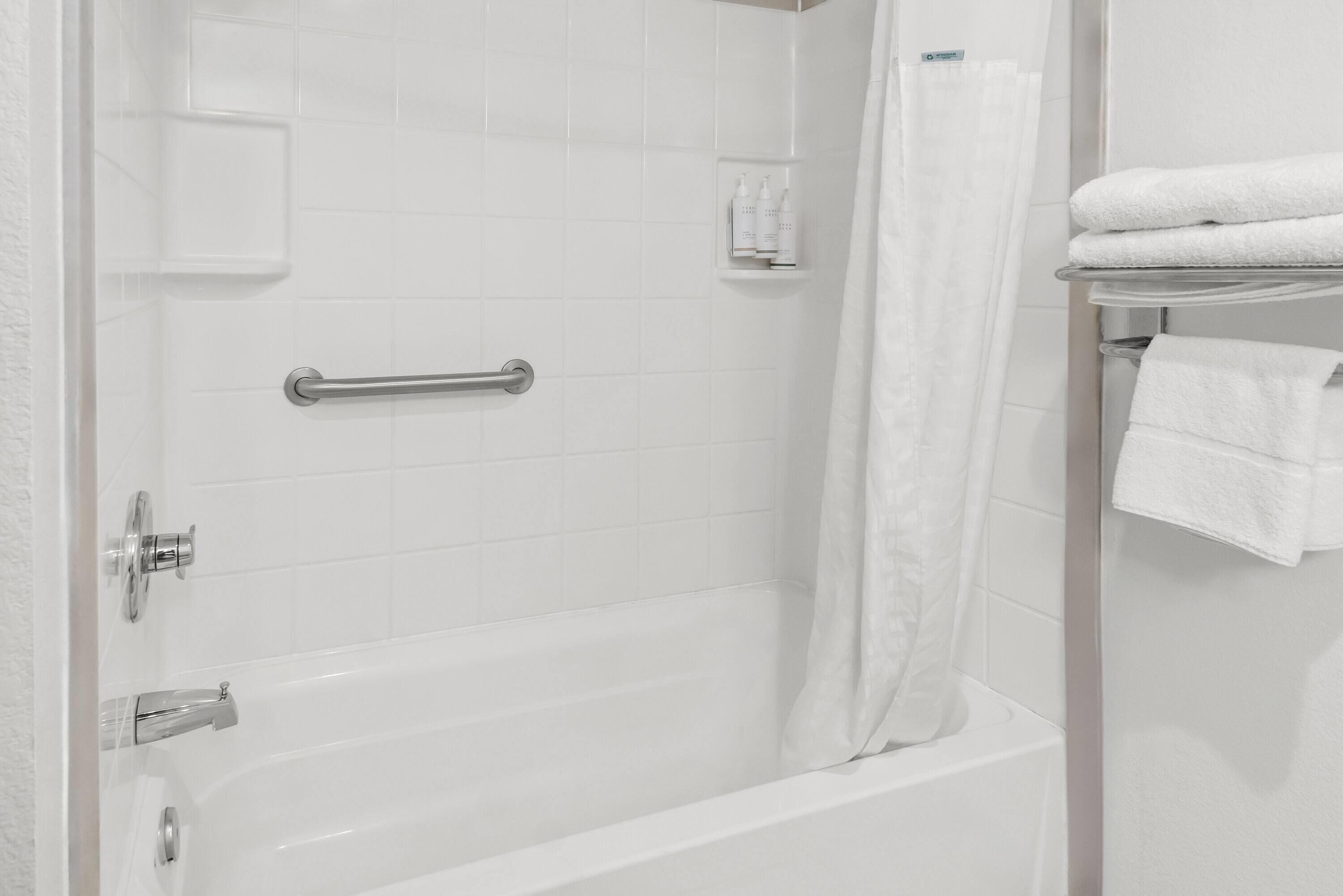 A modern bathroom with a bathtub, a shower curtain, and a towel rack.