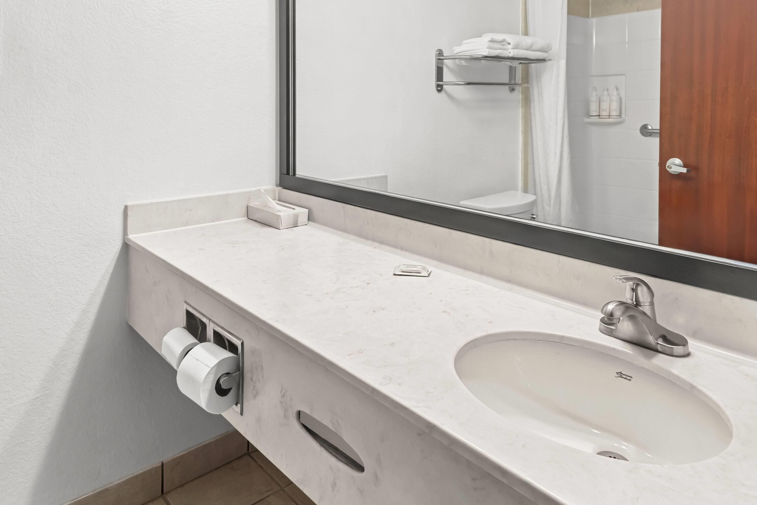 Un baño con lavamanos blanco, un espejo y un inodoro.