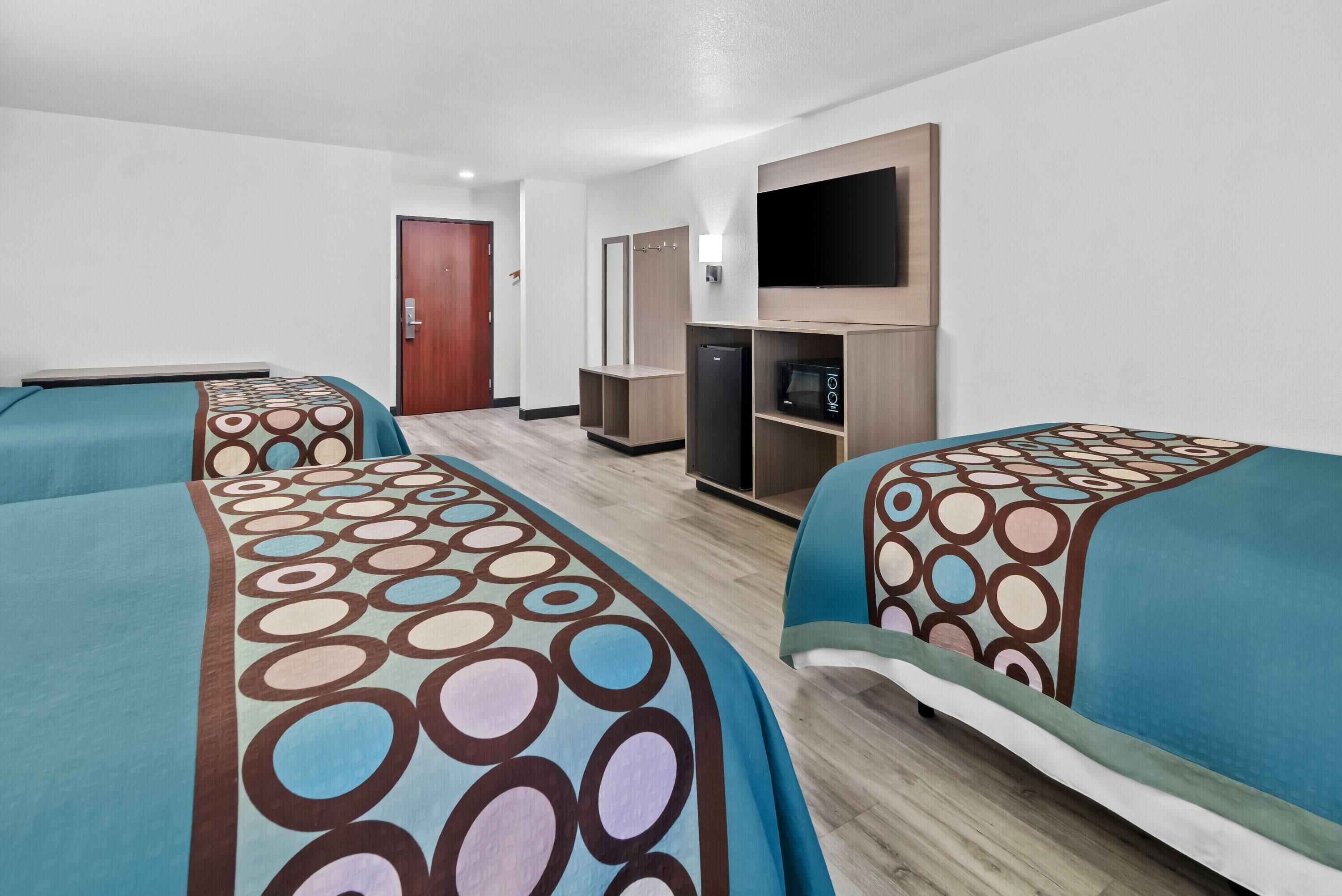 Une chambre d’hôtel avec deux lits, une télévision, un four à micro-ondes et un réfrigérateur.