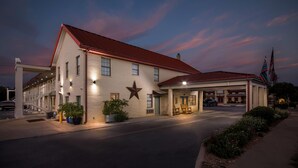 A motel with a red roof, a large star on the facade, and a flagpole with two flags. - Super 8 by Wyndham Fredericksburg (Fredericksburg)