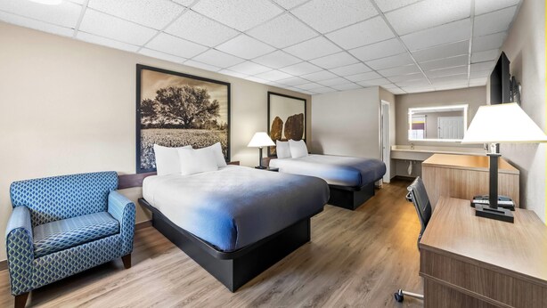 A hotel room with two beds, a sofa, a desk, and a lamp. - Super 8 by Wyndham Fredericksburg (Fredericksburg)