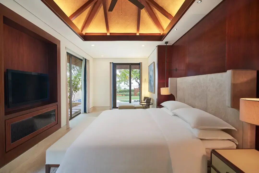 A hotel room with a large bed, a television, and a view of the outdoors.