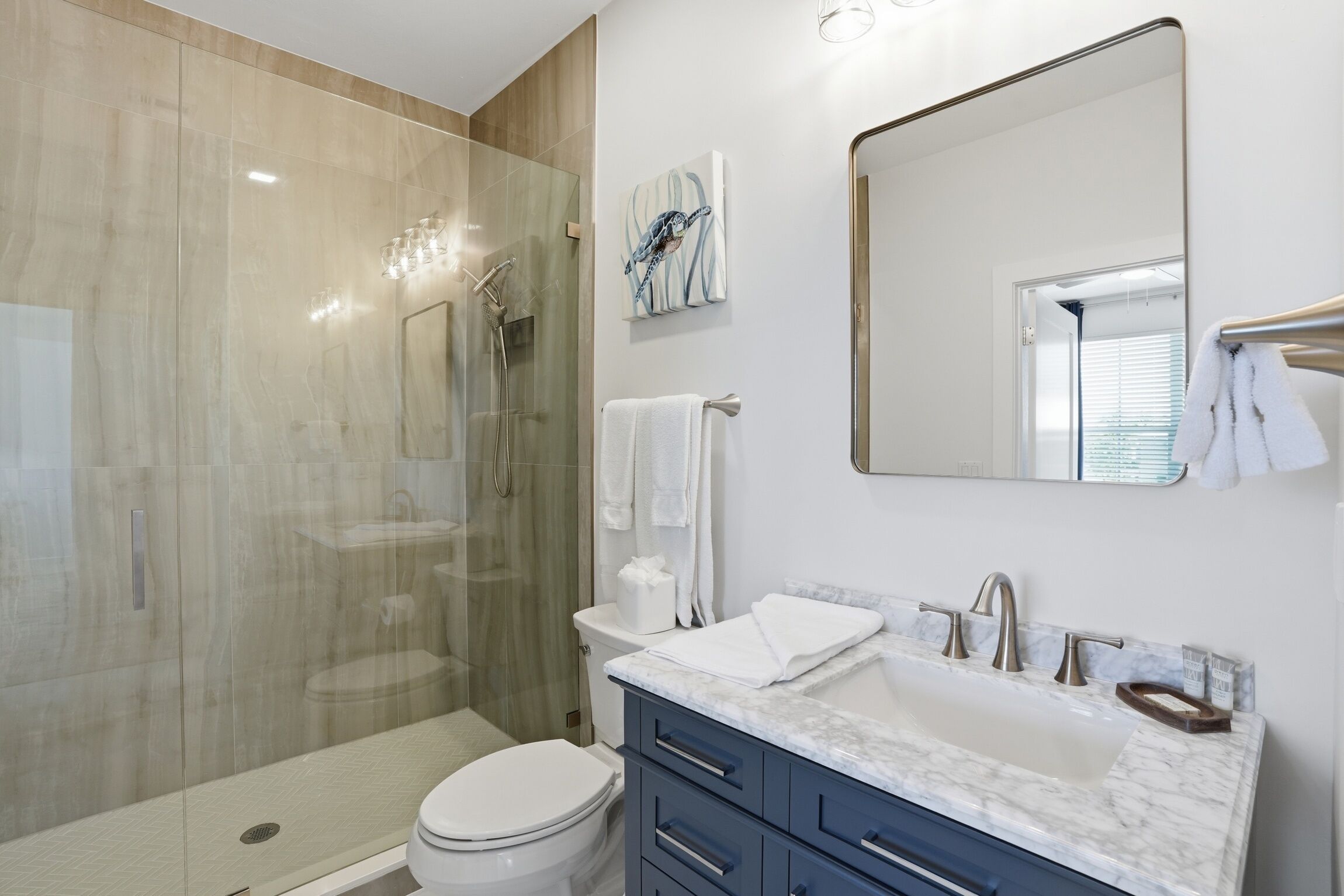 A modern bathroom with a glass-enclosed shower, a toilet, a sink with a marble countertop, and a large mirror.