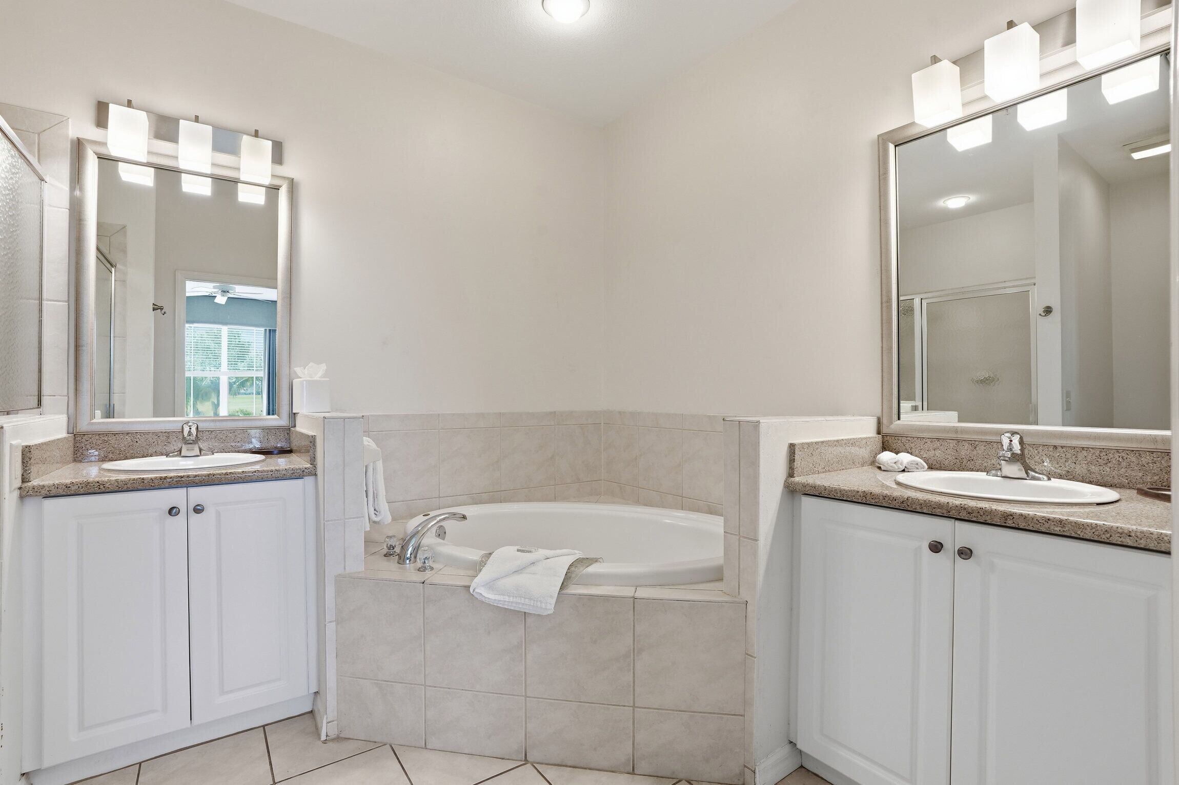 A bathroom with two sinks, a bathtub, and a large mirror.