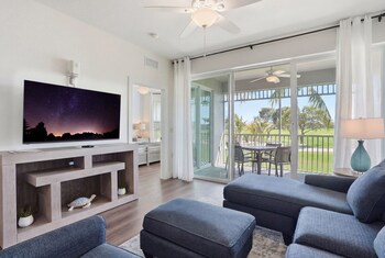 A golf course with a water body, sand bunkers, and palm trees. at GreenLinks Golf Villas at Lely Resort