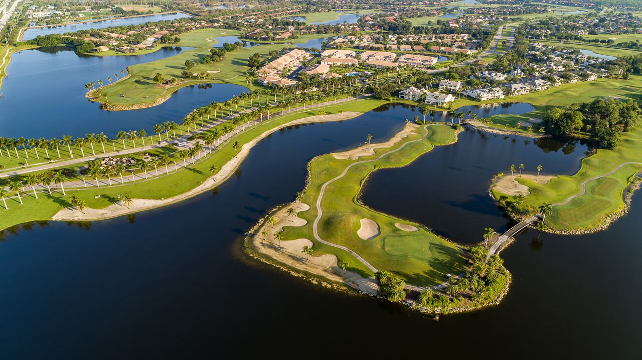 Vista aérea de un campo de golf con obstáculos acuáticos, búnkeres de arena y un puente.