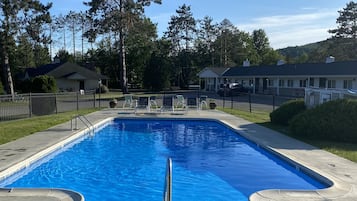 Una piscina al aire libre de temporada, sombrillas