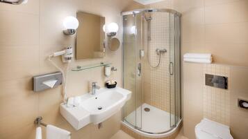 A modern bathroom with a glass-enclosed shower, a white sink, and a toilet.