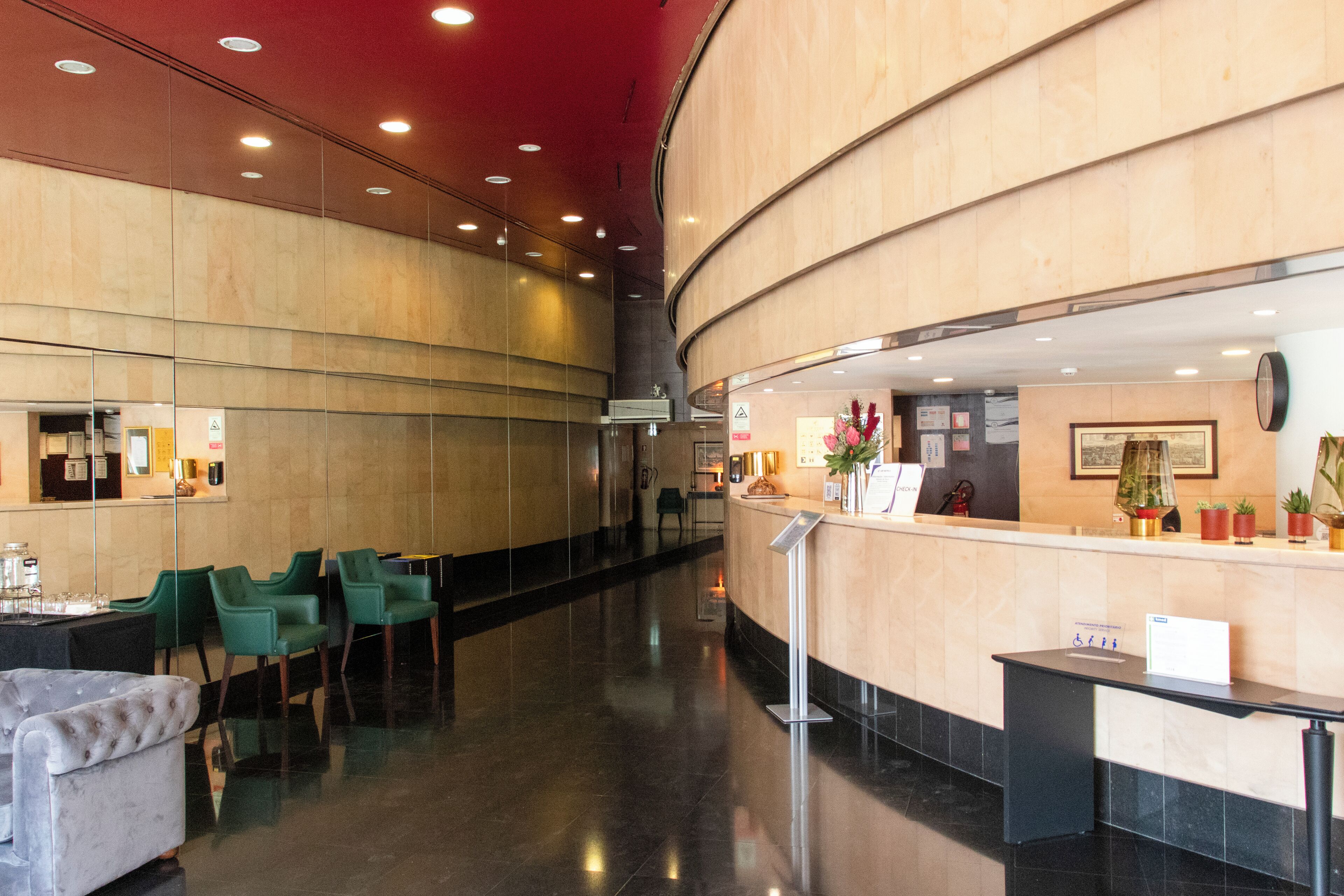 Eine moderne Hotelhalle mit einer Rezeption, grünen Stühlen und einer bequemen Sitzecke.