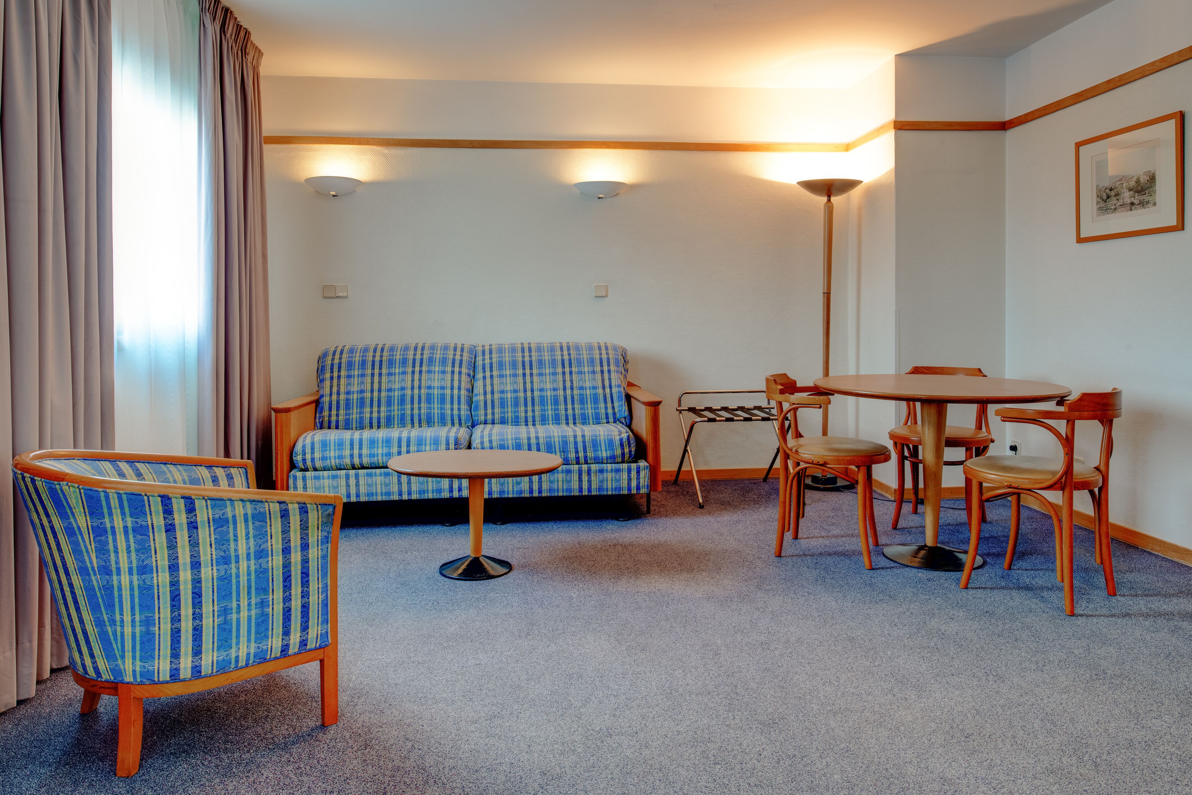 A living room with a sofa, a round table, and two chairs.
