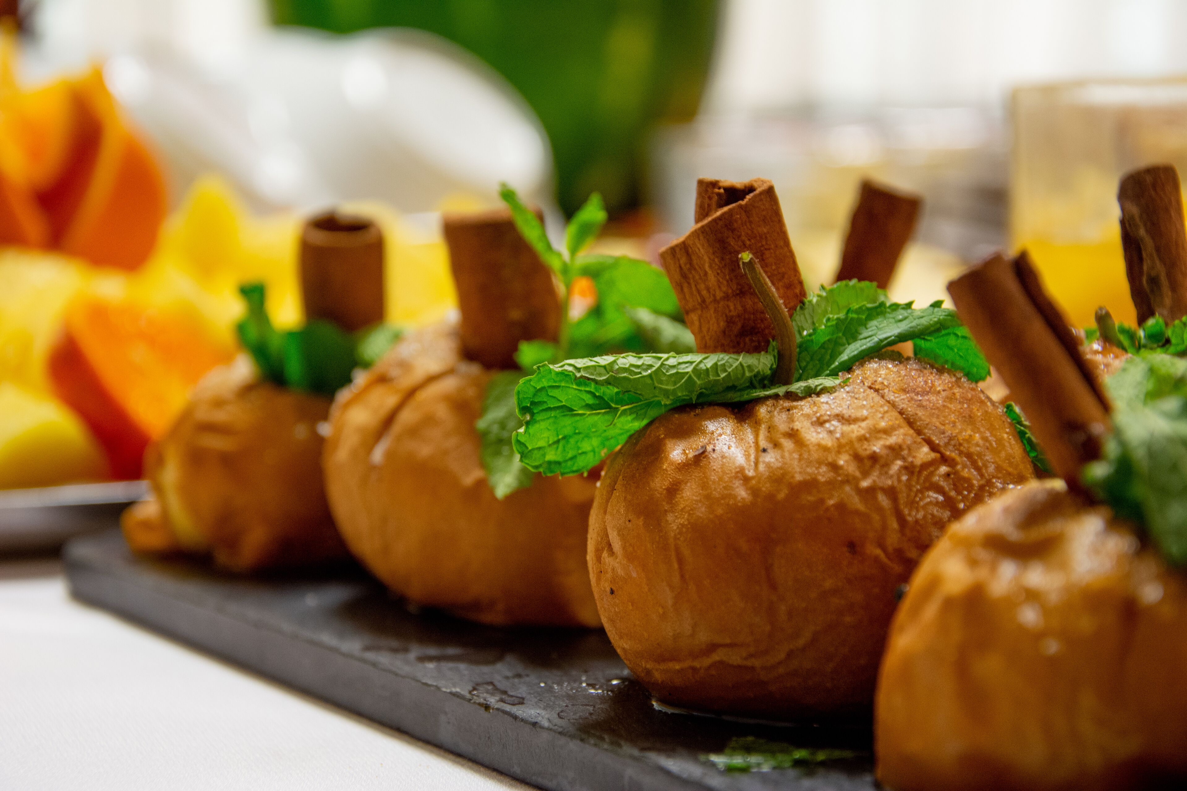 A close-up of a food display with pastries garnished with mint leaves and cinnamon sticks.