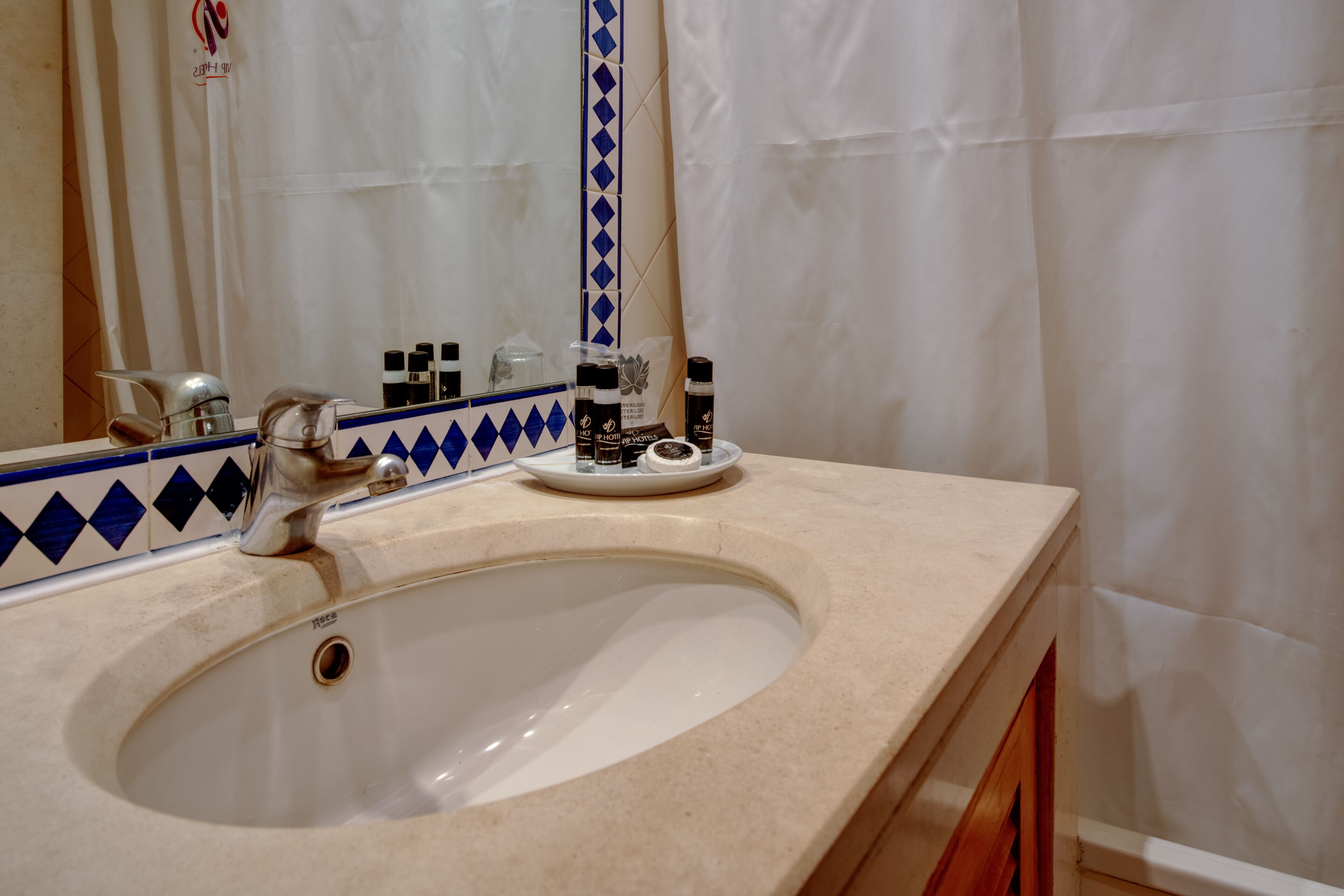 A bathroom with a sink, mirror, and toiletries.