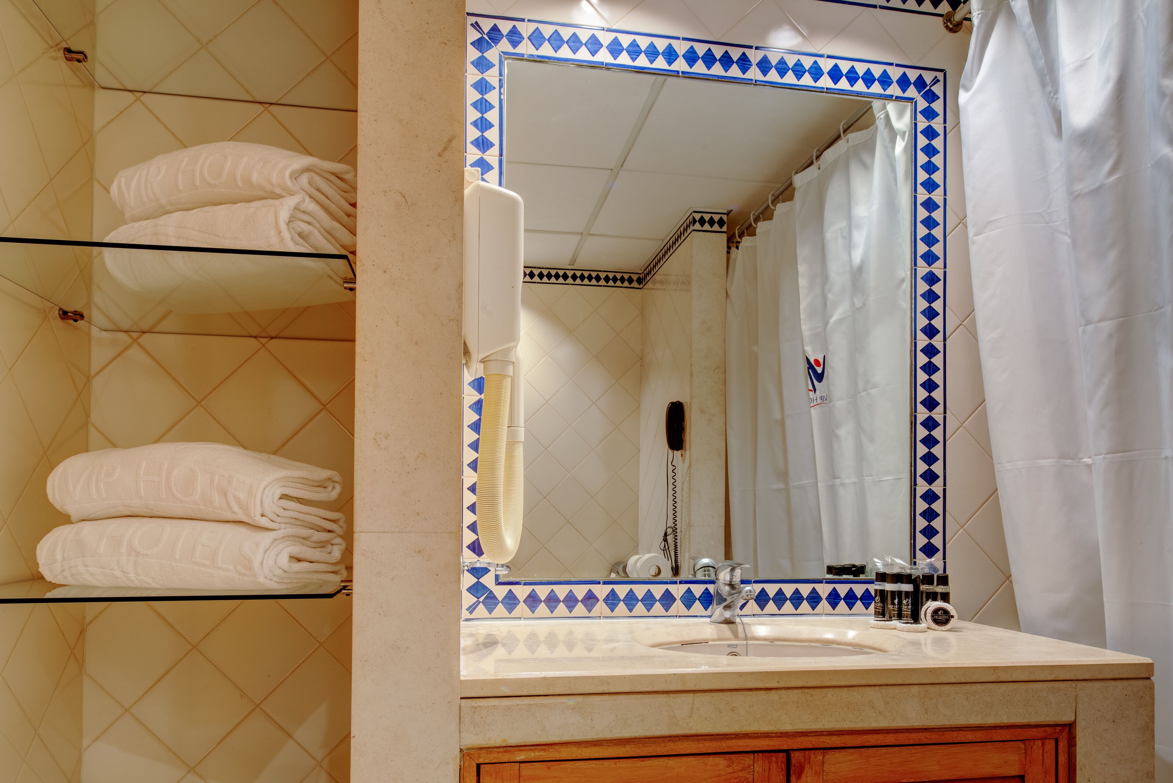 A bathroom with a tiled floor, a sink with a mirror, a towel rack, and a shower curtain.
