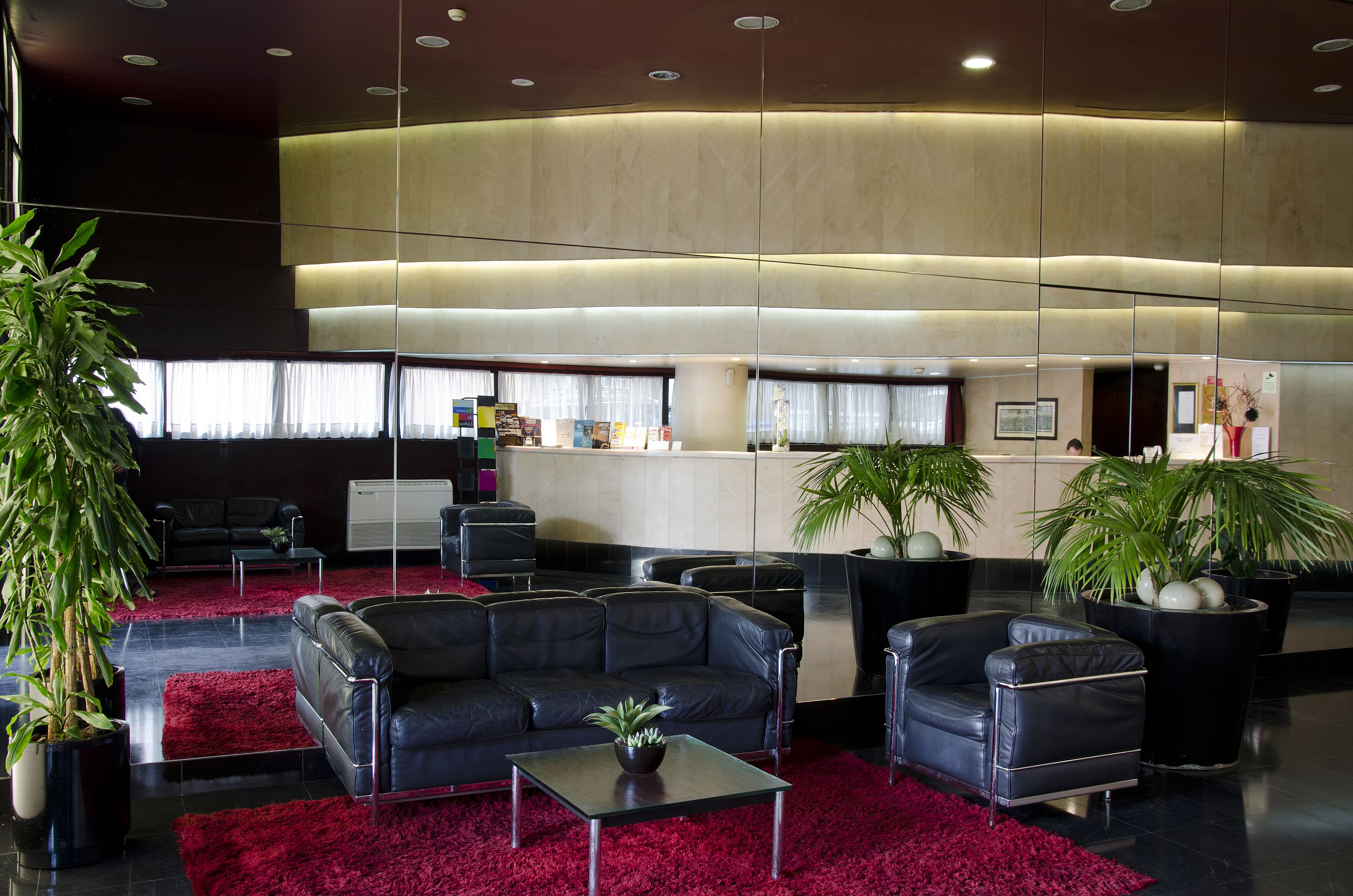 A modern lobby with leather sofas, a red carpet, and potted plants.