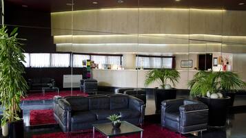 Een moderne lobby met leren banken, een rood tapijt en potplanten.