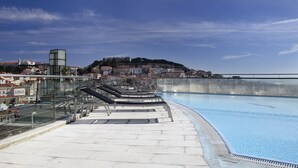 Une piscine dotée d’une balustrade en verre, avec une vue sur la ville en arrière-plan.
