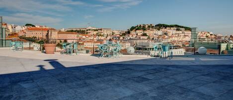A rooftop terrace with outdoor seating and a view of a cityscape.