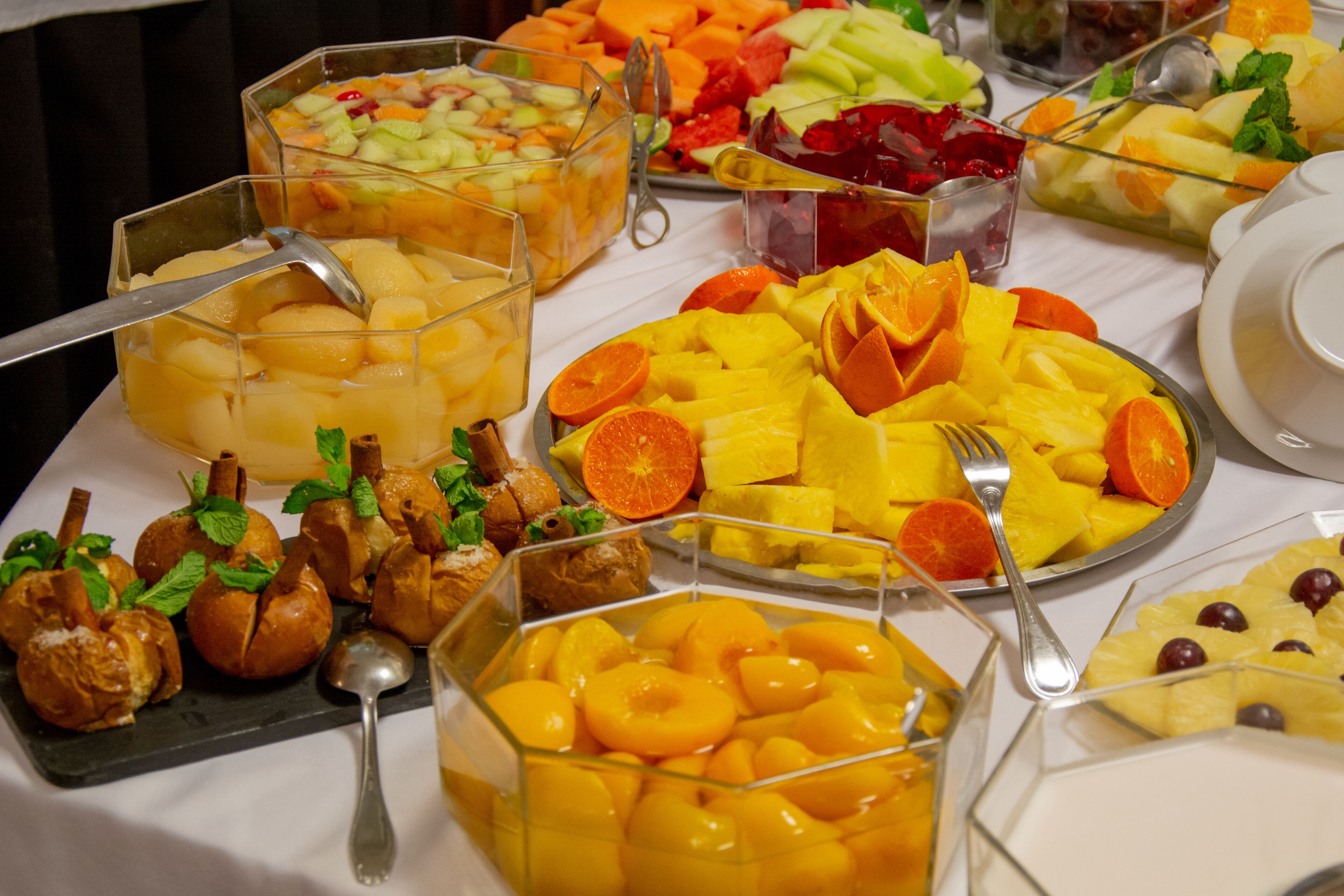 Monipuolinen buffet, jossa on tarjolla erilaisia hedelmiä ja jälkiruokia.