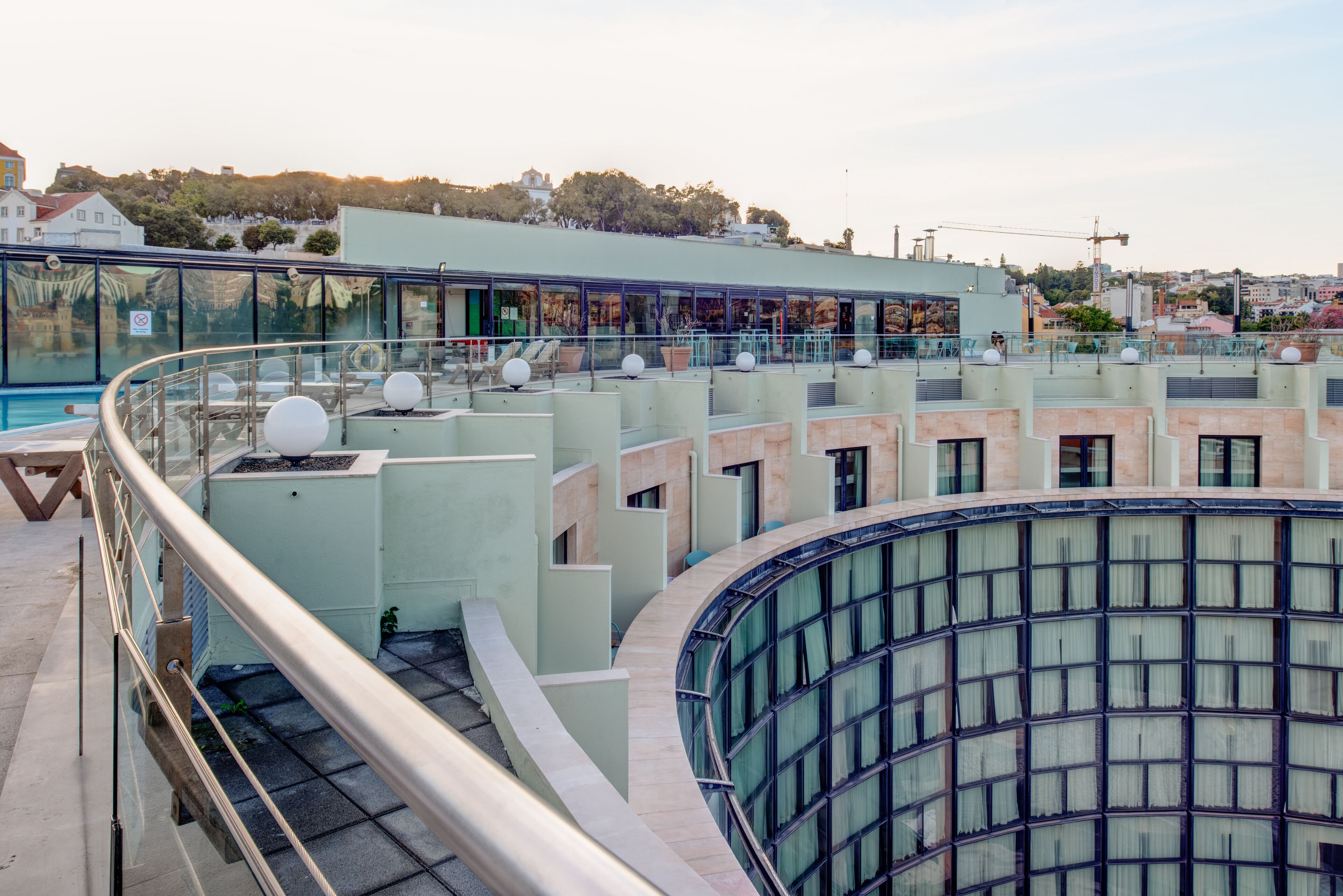 Un edificio moderno con fachada de vidrio, varios balcones y una zona de piscina.