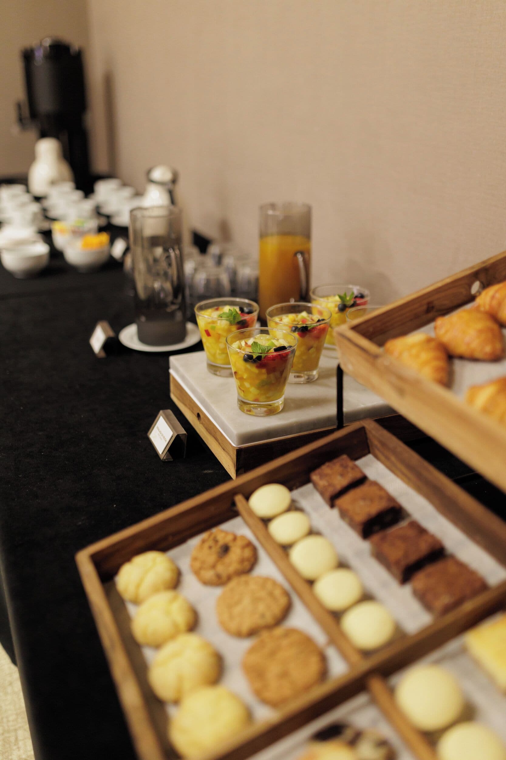 A buffet table with various food items including cookies, pastries, and fruit drinks.