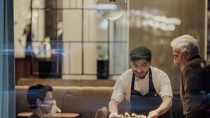 Un restaurante con una decoración moderna, que incluye lámparas colgantes y un separador de vidrio.