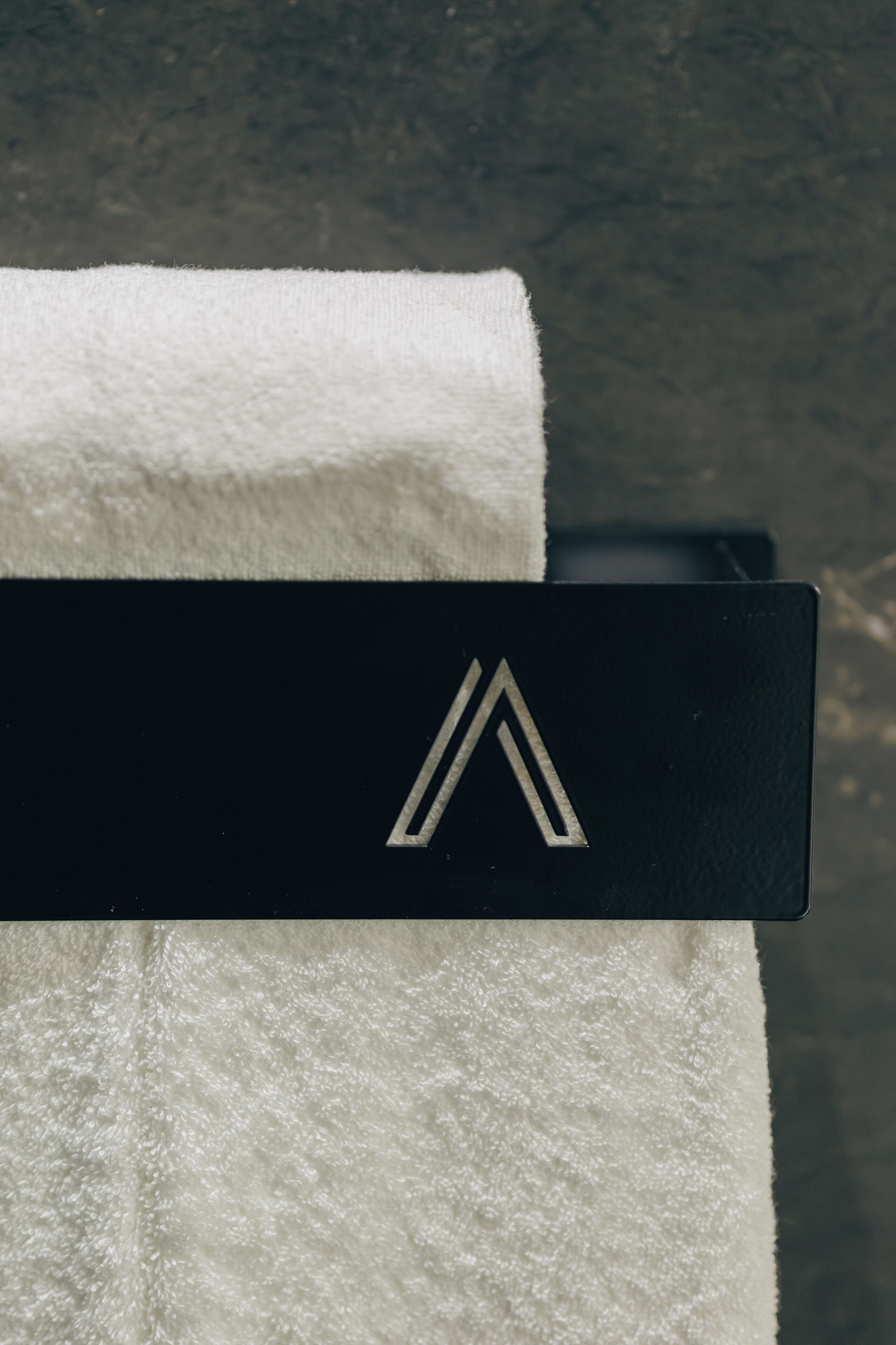 A white towel with a black tag featuring a geometric logo.