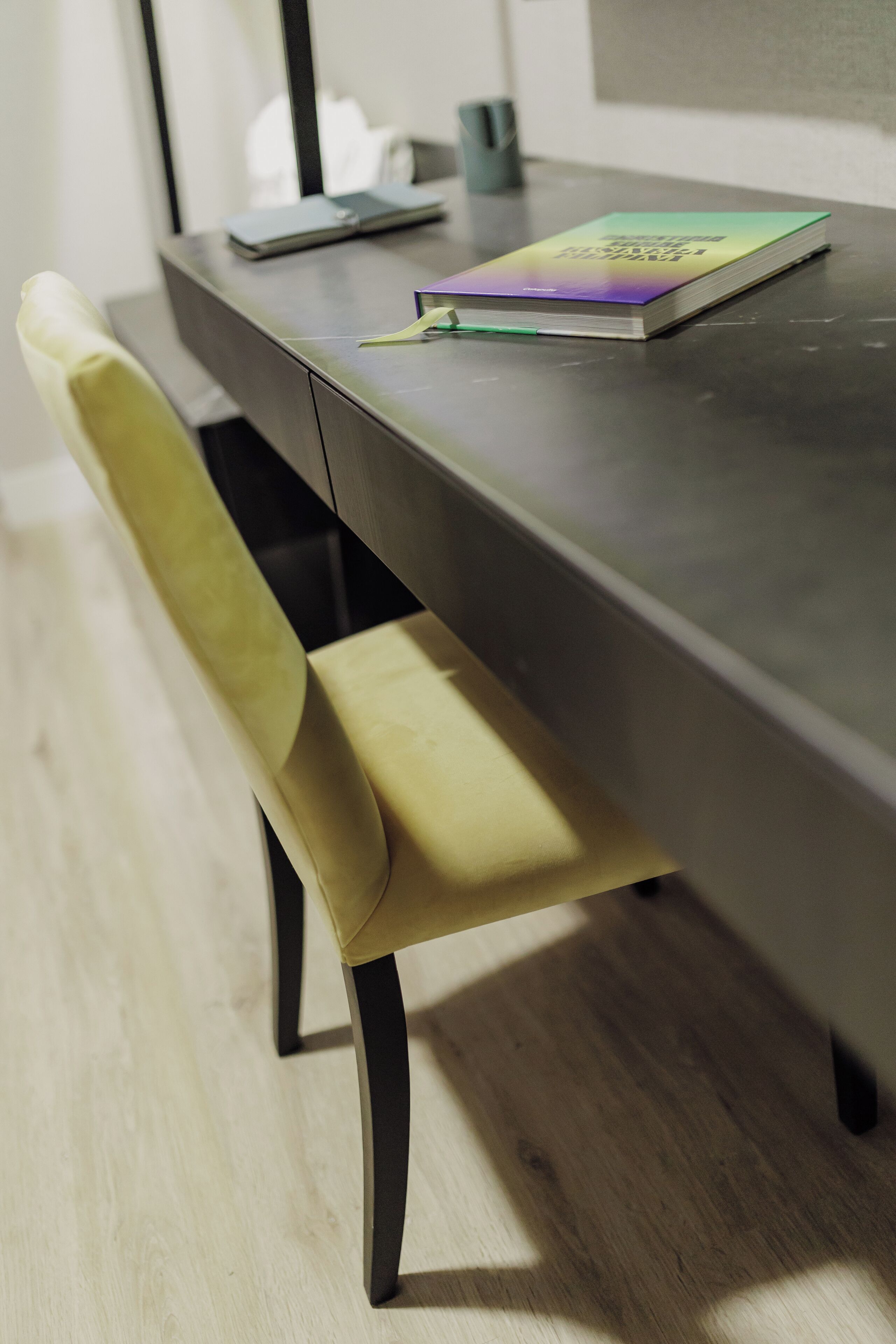 Une table à manger moderne avec un carnet et un stylo dessus, une chaise jaune et un smartphone en arrière-plan.