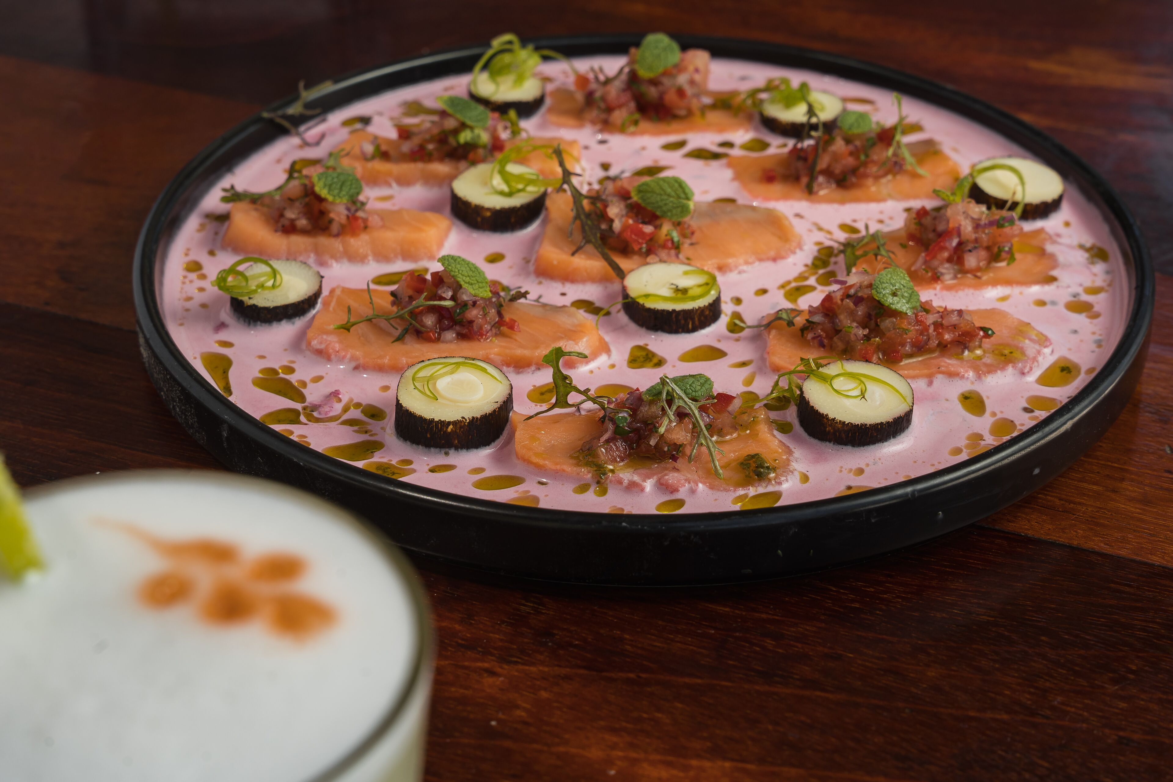 Una mesa redonda con un postre rosa y una bebida blanca.