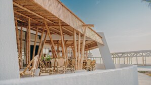 A covered outdoor seating area with bamboo furniture and a view of the sea. - Hotel Arica (Arica)