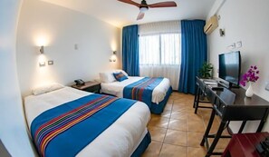 A hotel room with two beds, a desk with a chair, a television, and a ceiling fan. - Hotel Arica (Arica)