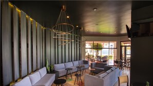 A modern lounge area with sofas, tables, and hanging light fixtures. - Hotel Arica (Arica)