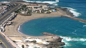 An aerial view of a coastal area with a beach, a road, and buildings. - Hotel Arica (Arica)