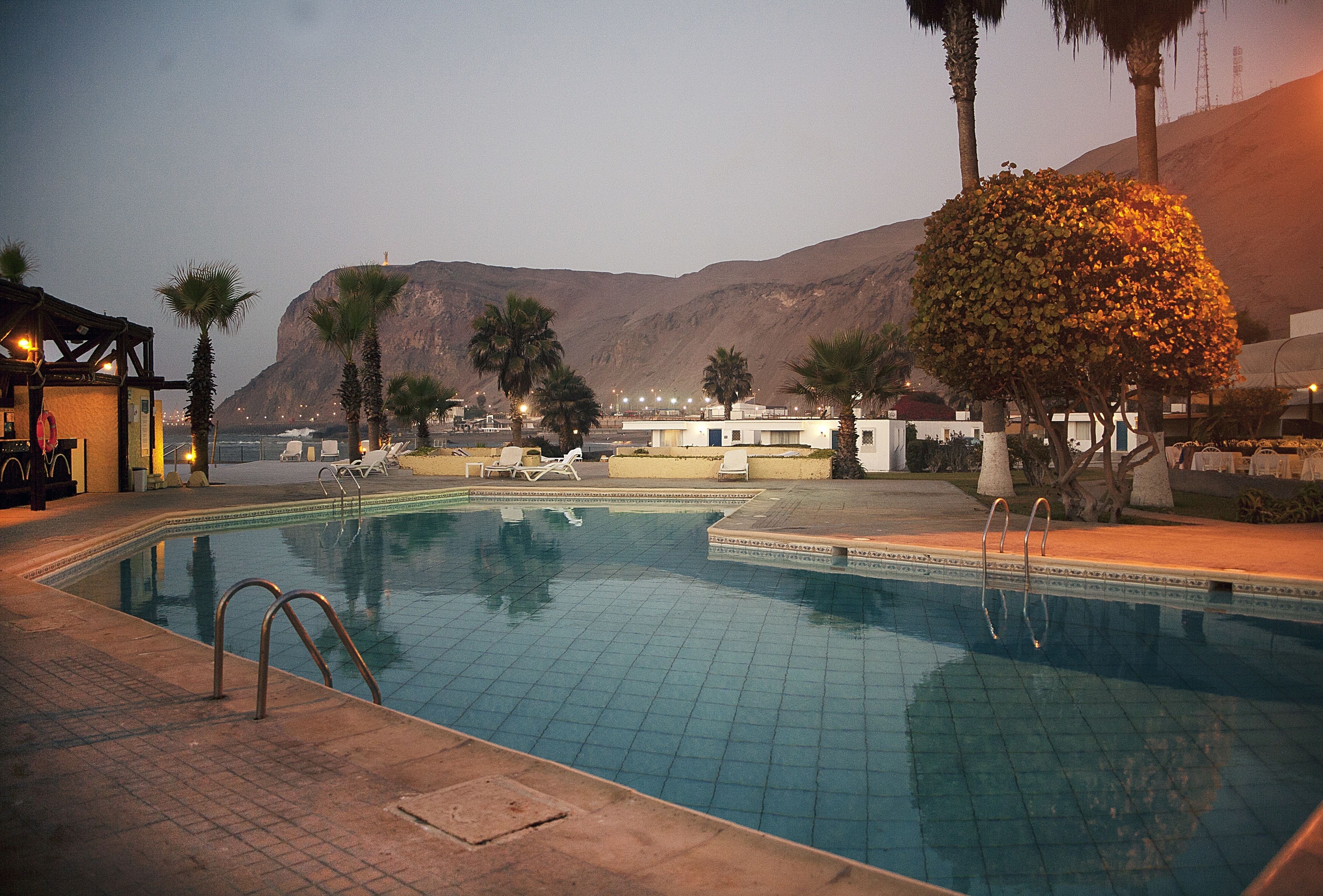 A swimming pool with a view of mountains and a building in the background.
