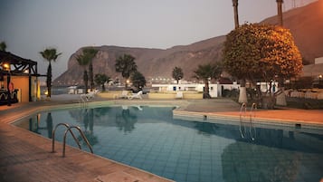 A swimming pool with a view of mountains and a building in the background.