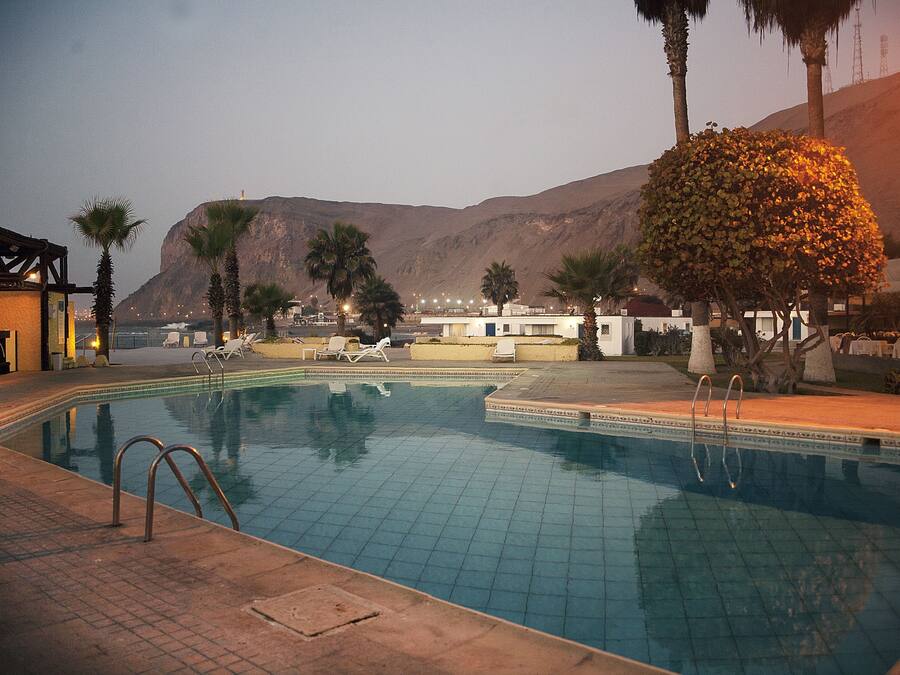 A swimming pool with a view of mountains and a building in the background.