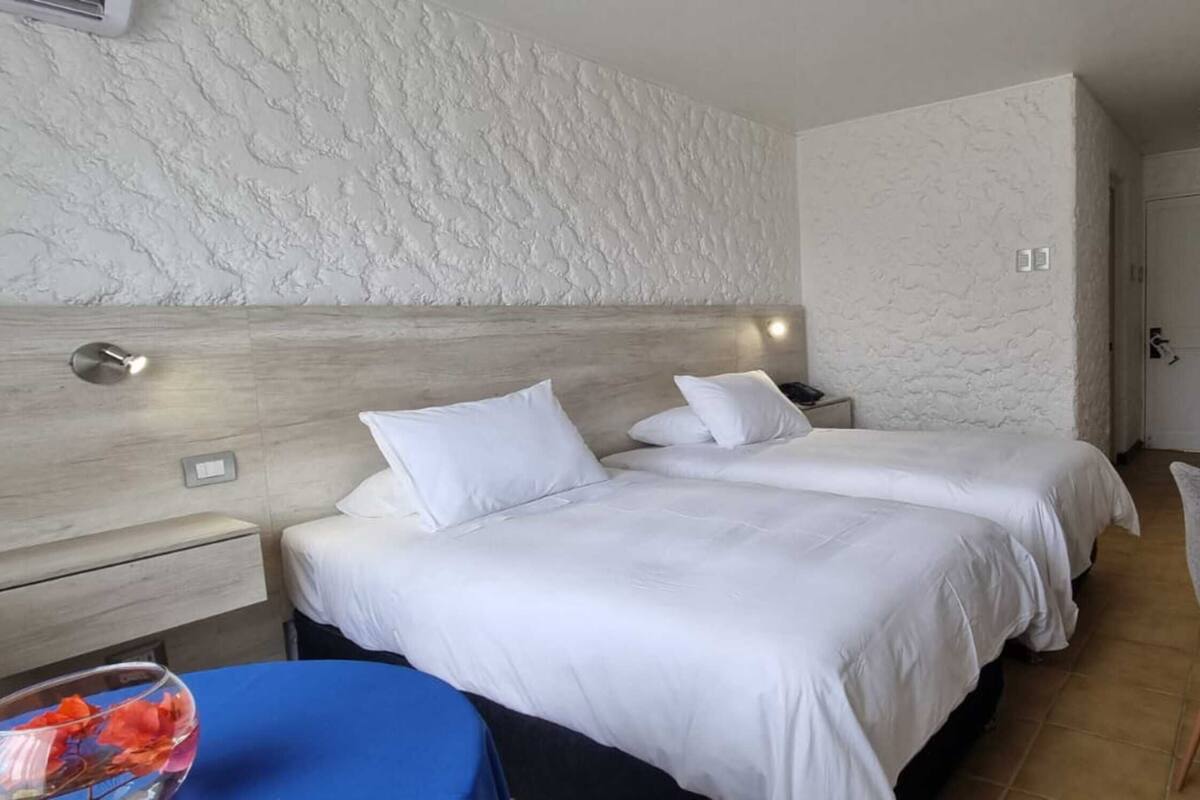 A hotel room with two beds, a desk, and a TV.