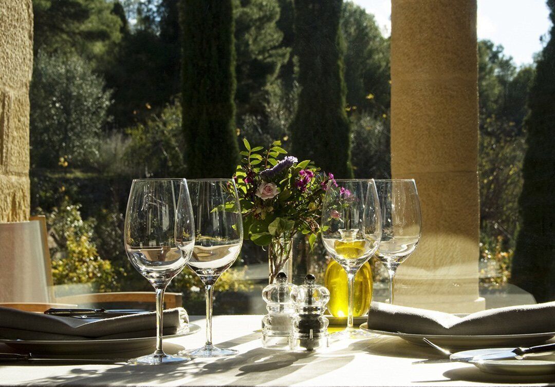 A table set for dining with wine glasses, a vase with flowers, and salt and pepper shakers.