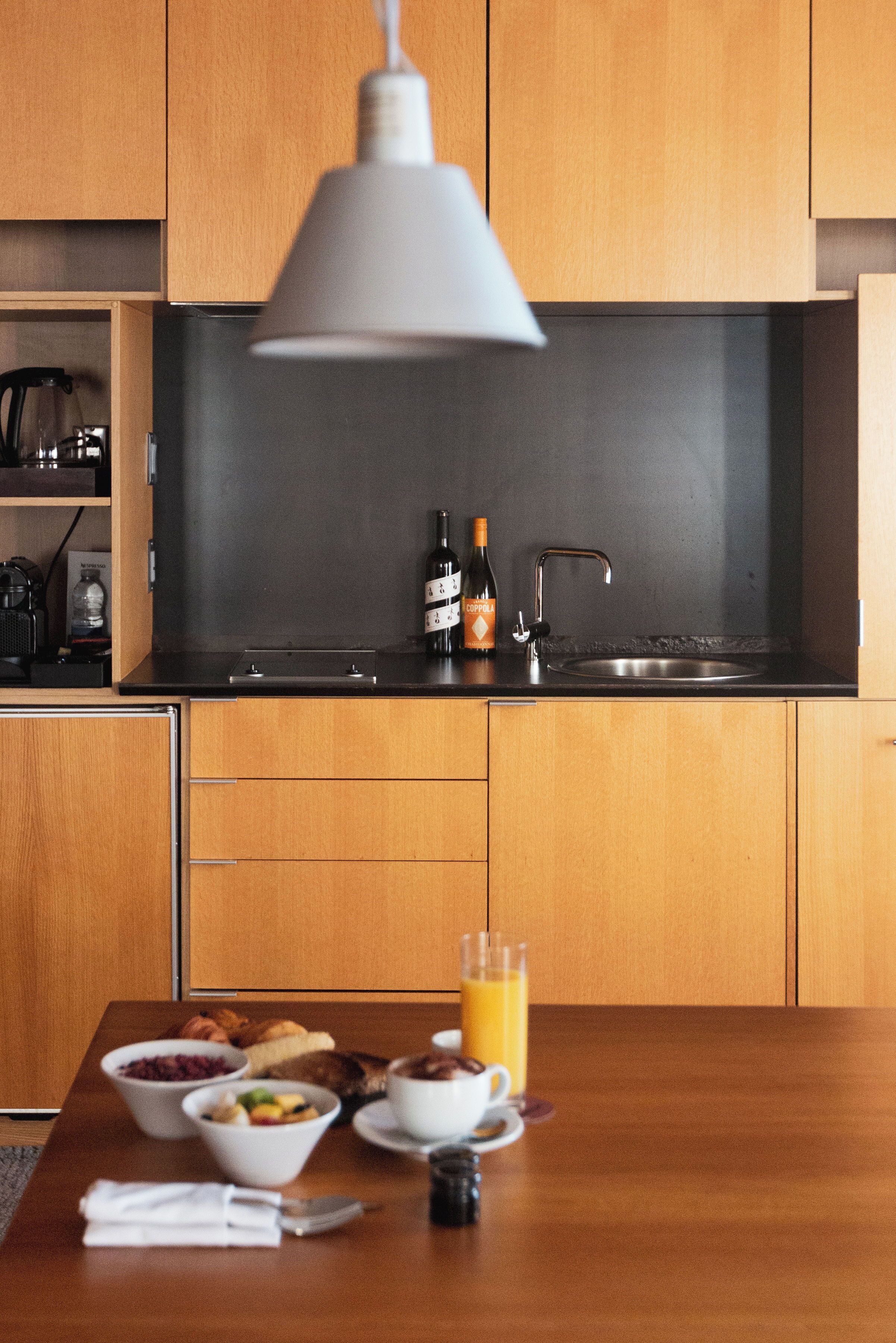 Een moderne keuken met houten kastjes, een zwart aanrecht en een hangende lamp.