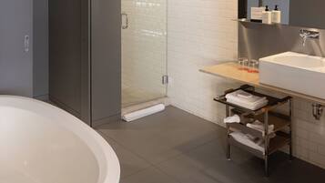 A modern bathroom with a freestanding bathtub, a glass-enclosed shower, and a vanity with a mirror and sink.