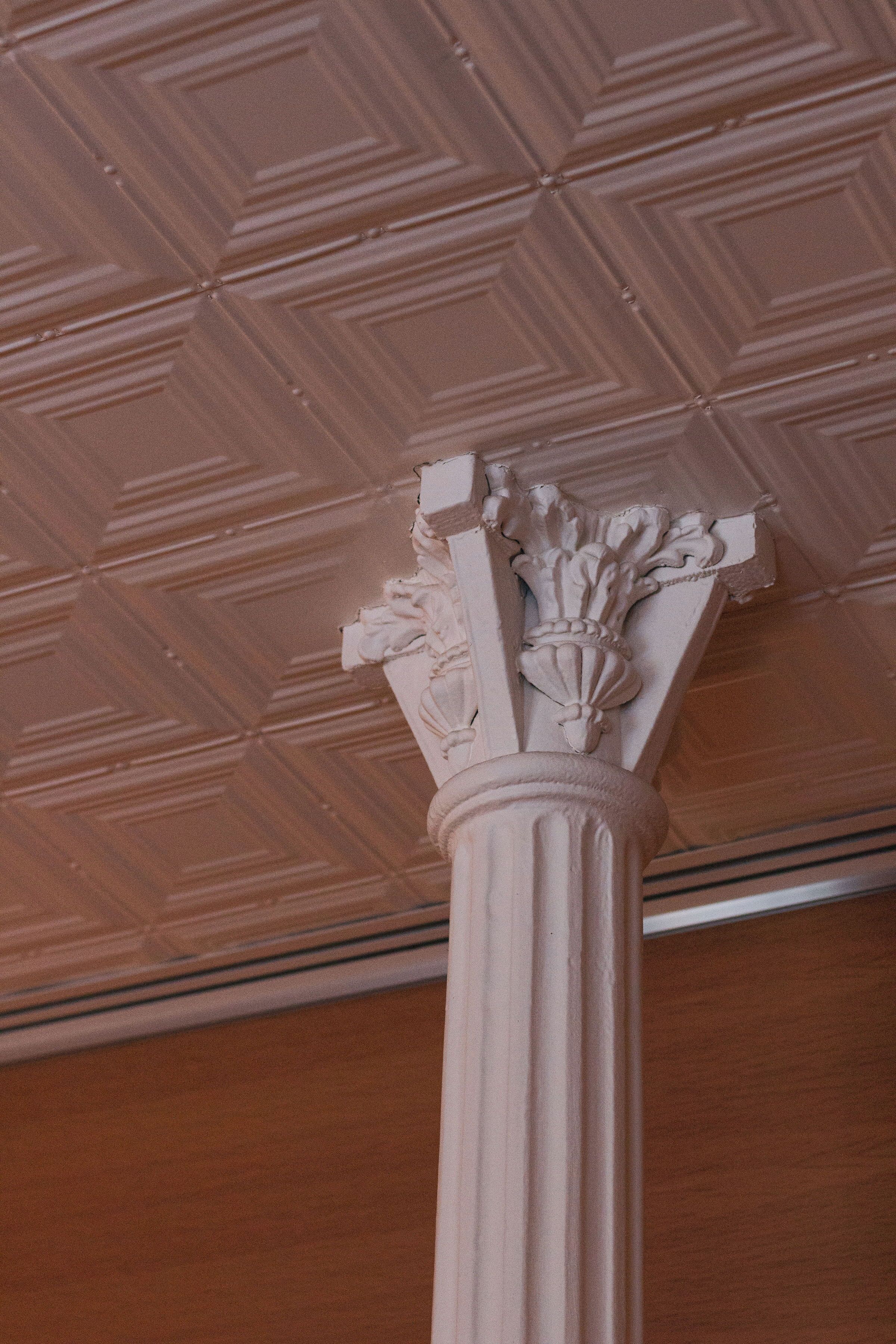 Un techo con un diseño geométrico y una columna clásica con capiteles ornamentados.